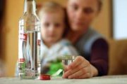 Butelka wódki na tle kobiety z dzieckiem