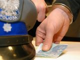 policyjna czapka, gotówka i kajdanki