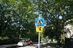 Znak drogowy zasłonięty przez drzewo