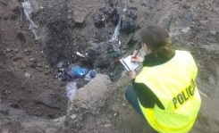 Policjant podczas oględzin miejsca nielegalnego składowania śmieci