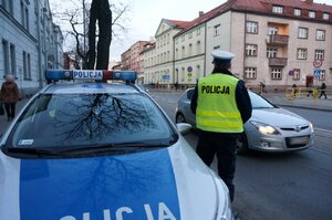 Policjant ruchu drogowego stojący przy policyjnym radiowozie w rejonie przejścia dla pieszych przy ul. 3 Maja w Zabrzu