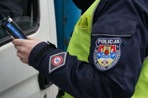 Ręka policjanta trzymająca urządzenie do pomiaru zawartości alkoholu w wydychanym przez kierującego powietrzu