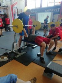 Policjant wyciskający sztangę leżąc asekurowany przez drugiego zawodnika