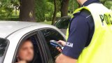 Policjant zabrzańskiej drogówki podczas kontroli drogowej, w trakcie której sprawdza stan trzeźwości kierującego samochodem osobowym