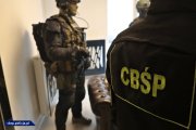 Zdjęcie kolorowe- dwóch uzbrojonych policjantów CBŚP na klatce schodowej