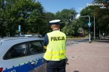 Zdjęcie kolorowe: policjant zabrzańskiej drogówki stojący obok radiowozu w rejonie oznakowanego przejścia dla pieszych