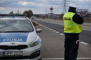 Zdjęcie kolorowe: policjant zabrzańskiej drogówki przy policyjnym radiowozie  na Drodze Krajowej nr 88 w trakcie pomiaru prędkości