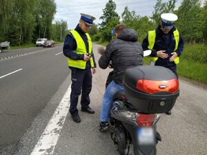 Zdjęcie kolorowe: umundurowani policjanci zabrzańskiej drogówki podczas kontroli drogowej kierującego skuterem na DK 88