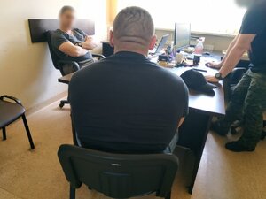 Zdjęcie kolorowe: pokój w KMP Zabrze, dwóch nieumundurowanych policjantów w towarzystwie zatrzymanego męzczyzy