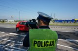 zdjęcie kolorowe: policjant ruchu drogowego wykonuje pomiar prędkości na drodze.