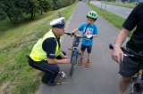 Zdjęcie kolorowe: policjant montuje, odblask na rowerze dziecka.