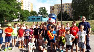 Zdjęcie kolorowe:  Policjant wraz  z  grupą dzieci oraz  sznupkime