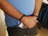 zdjęcie kolorowe: osoba z  założonymi na  ręce kajdankami