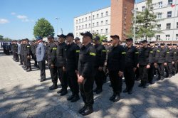 Zdjęcie kolorowe: nowo przyjęci policjanci na placu apelowym składający przysięgę