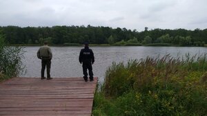 Zdjęcie kolorowe: Umundurowany funkcjonariusz Lasów Państwowych Nadleśnictwa Brynek z funkcjonariuszem Komendy miejskiej Policji w zabrzu podczas kontroli zbiorników wodnych