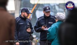Zdjęcie kolorowe: umundurowani policjanci z patrolu rozmawiją z kobietą