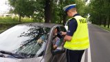 Zdjęcie kolorowe: umundurowany policjant zabrzańskiej drogówki na drodze podczas kontroli trzeźwości kierującego samochodem osobowym