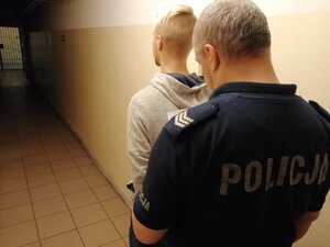 zdjęcie kolorowe: policjant prowadzi zatrzymanego