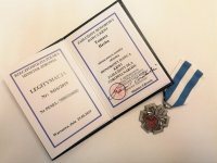 Zdjęcie kolorowe: policjant otrzymuje medal honorowego krwiodawstwa