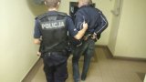 Zdjęcie kolorowe:  zatrzymany mężczyzna prowadzony przez  policjanta.