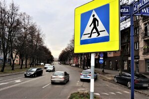 Zdjęcie kolorowe: radiowóz obok przejścia dla pieszych.