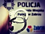 zdjęcie kolorowe: kajdanki na tle baneru policja Zabrze.