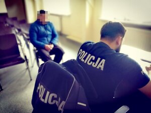 zdjęcie kolorowe: policjant podczas wykonywania dokumentacji z zatrzymaną osobą poszukiwaną.