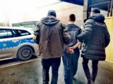 Zdjęcie kolorowe: policjanci operacyjni prowadzą zatrzymanego