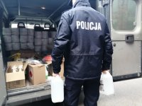 Zdjęcie kolorowe: policjant pobiera środki ochrony w postaci płynów dezynfekujących.