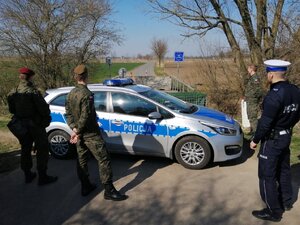 Zdjęcie kolorowe: policjanci wspólnie z  żołnierzami pilnują przejścia granicznego.