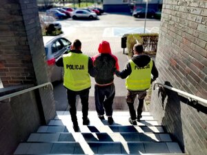 Zdjęcie kolorowe: policjanci prowadzą zatrzymanego