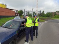 Zdjęcie kolorowe: Policjant i funkcjonariusz SOK rozmawiają z kierowcą pojazdu podczas działań  &quot;bezpieczny przejazd&quot;.