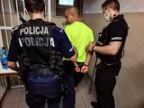 Zdjęcie kolorowe: policjanci prowadzą zatrzymanego mężczyznę.