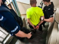 Zdjęcie kolorowe: policjanci prowadzą zatrzymanego mężczyznę.