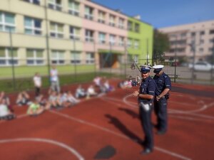 Zdjęcie kolorowe: policjancie ruchu drogowego podczas prelekcji w szkole podstawowej.