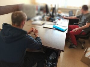 Zdjęcie kolorowe: policjant podczas przesłuchania  osoby zatrzymanej