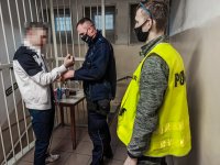 zdjęcie kolorowe: policjanci prowadzą zatrzymanego mężczynę