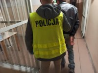 Policjanci ubranie w kamizelki odblaskowe doprowadzaj zatrzymanego na czynności