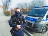 Sierżant Michał Wójcik stojący obok radiowozu