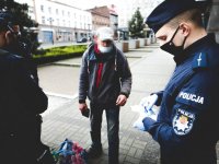 Policjant daje maskę ochronną osobie na ulicy