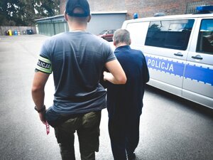 Policjant prowadzi zatrzymanego mężczyznę