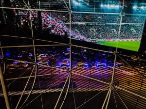 Pojazdy policyjne przed stadionem i widok trybun widziany w odbiciu szyby podczas Zabezpieczenia meczu Górnika Zabrze z Legią Warszawa