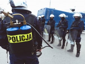 Policjant z plecakowym miotaczem gazu