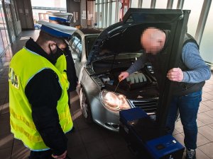 Policjanci podczas  akcji Twoje światła - Nasze bezpieczeństwo na stacji kontroli pojazdów przy sprawdzaniu oświetlenia pojazdu