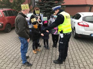 Policjanci WRD KMP Zabrze podczas  zabezpieczenia orszaku trzech króli rozdają odblaski