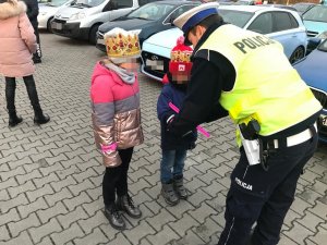 Policjanci WRD KMP Zabrze podczas  zabezpieczenia orszaku trzech króli rozdają odblaski