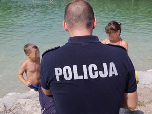 Zdjęcia kolorowe: Umundurowani policjanci wspólnie z ratownikami Wodnego Ochotniczego Pogotowia Ratunkowego, na terenie Kąpieliska Leśnego rozmawiają z dziećmi i młodzieżą na temat bezpieczeństwa nad wodą.