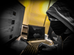 Zamaskowana postać przed ekranem monitora