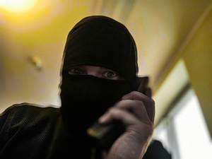Zamaskowana osoba trzymającą telefon