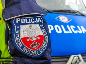 Naszywka policji na  tle radiowozu ruchu drogowego